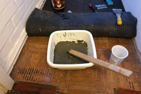 A washing up bowl of wet cement with a wooden stick used for mixing