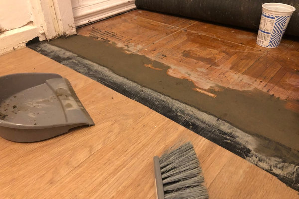 Wet cement bridging the gap between the inside vinyl floor and the porch carpet
