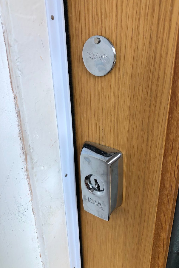 White brush strip running vertical beside the lock and deadbolt