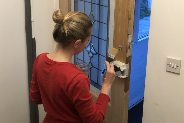 My wife applying Danish oil to the door. The shiny metalwork is masking taped.