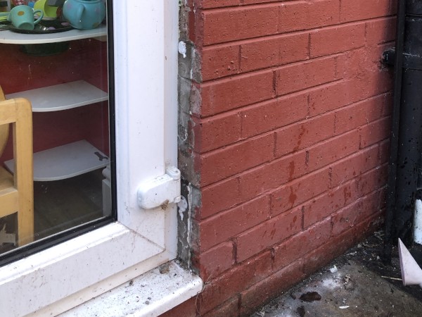 Outside view of the french door with broken red bricks filled up with mortar.
