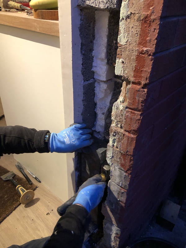 A pair of hands replacing bricks in the window reveal.