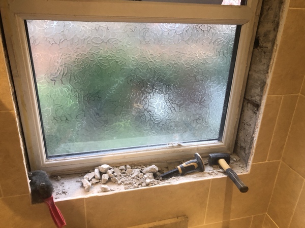 Plaster rubble all around the bathroom window. The reveals are back to brick while maintaining the wall tiles.