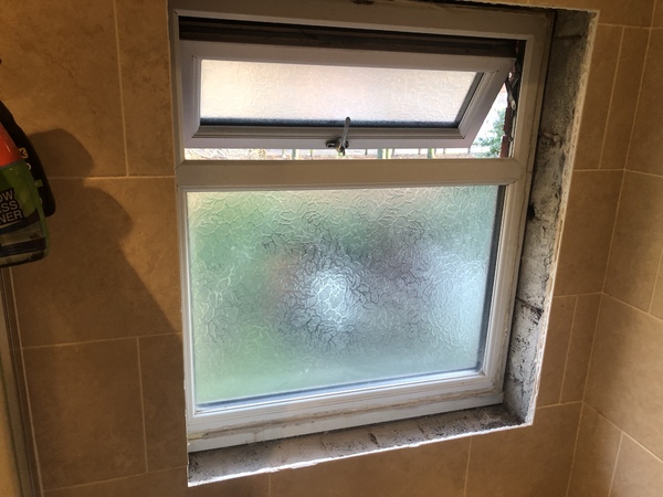 The bathroom window with visible breeze block all around the reveals while maintaining the wall tiles.