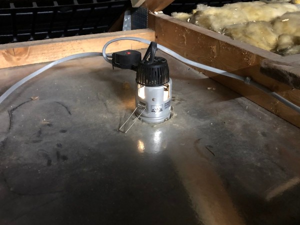 Inside the loft, a spotlight enclosure fitted into plasterboard with a floating wire